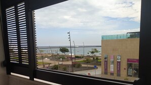Vista desde una ventana con persianas, que da a una calle con un edificio identificado como 'hormicasa'.