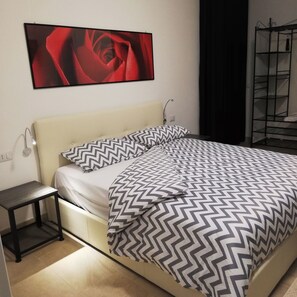 Cozy retreat with a neatly made bed, bedside table, and framed artwork.