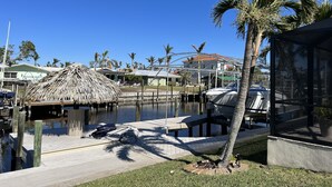A marina with boats docked, a thatched structure, and palm trees. - Villa Nautica - Perfect for boaters (Cape Coral)