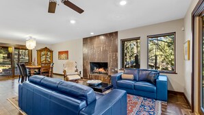 A spacious living room with a fireplace, leather sofas, and large windows offering a view of the outdoors. - Slippery Rock Vacation Home - sleeps 9 (Flagstaff)