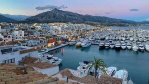 A marina filled with boats, a town with white buildings, and mountains in the background. - Spectacular Penthouse with panoramic sea views in Riviera del Sol (Mijas-Costa)