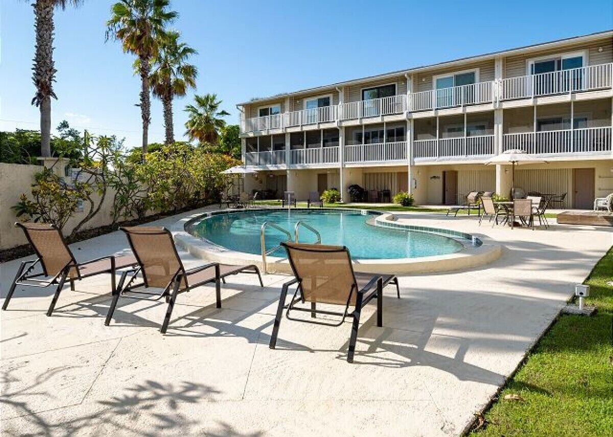 A hotel with a pool, outdoor seating, and a two-story building.