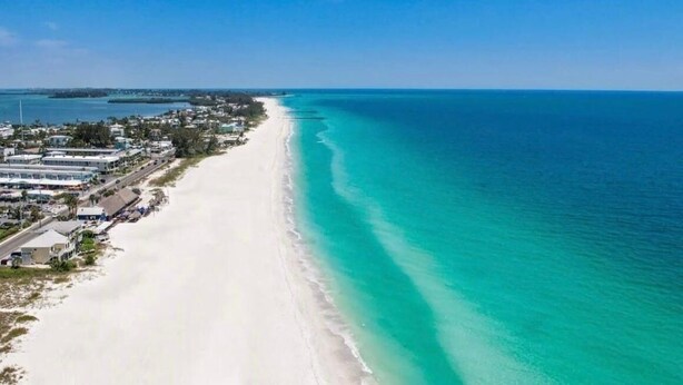 A coastal area with a sandy beach and a clear blue sea.