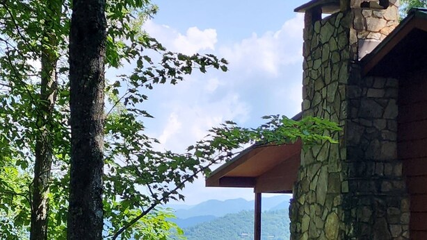 Un bâtiment en pierre doté d’un balcon donnant sur une zone boisée et un lac.