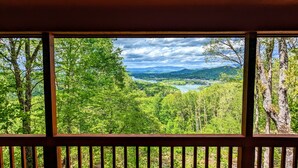Une terrasse en bois offrant une vue sur une vallée verdoyante et une rivière.
