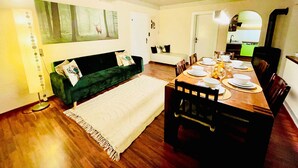 A dining area with a wooden table set for four, a green sofa, and a painting of a forest scene. - Gemütliche Ferienwohnung im Dorfzentrum mit Garten für 2- 6 Personen (Aschau im Zillertal)