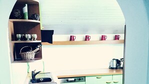 A kitchen with a dishwasher, a sink, and a countertop. There are shelves with cups and a basket. - Gemütliche Ferienwohnung im Dorfzentrum mit Garten für 2- 6 Personen (Aschau im Zillertal)