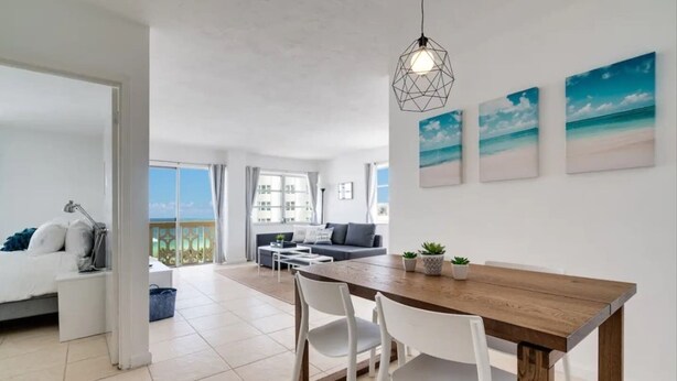 A modern apartment with a dining area, a sofa, and a view of the sea. - Miami Beach Getaway| Ocean & City Views + FastWiFi (Miami)