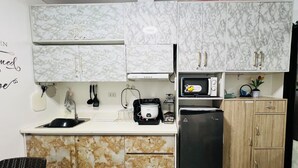 Una cucina compatta con mobili in marmo, un frigorifero nero, un forno a microonde e un lavandino.