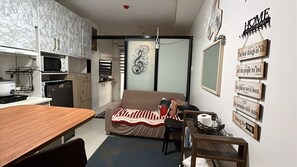 A compact living space with a kitchenette, a sofa, a dining table, and a wall with motivational signs. - Samboy Condo unit besides SM Mall uptown (Cagayan de Oro)
