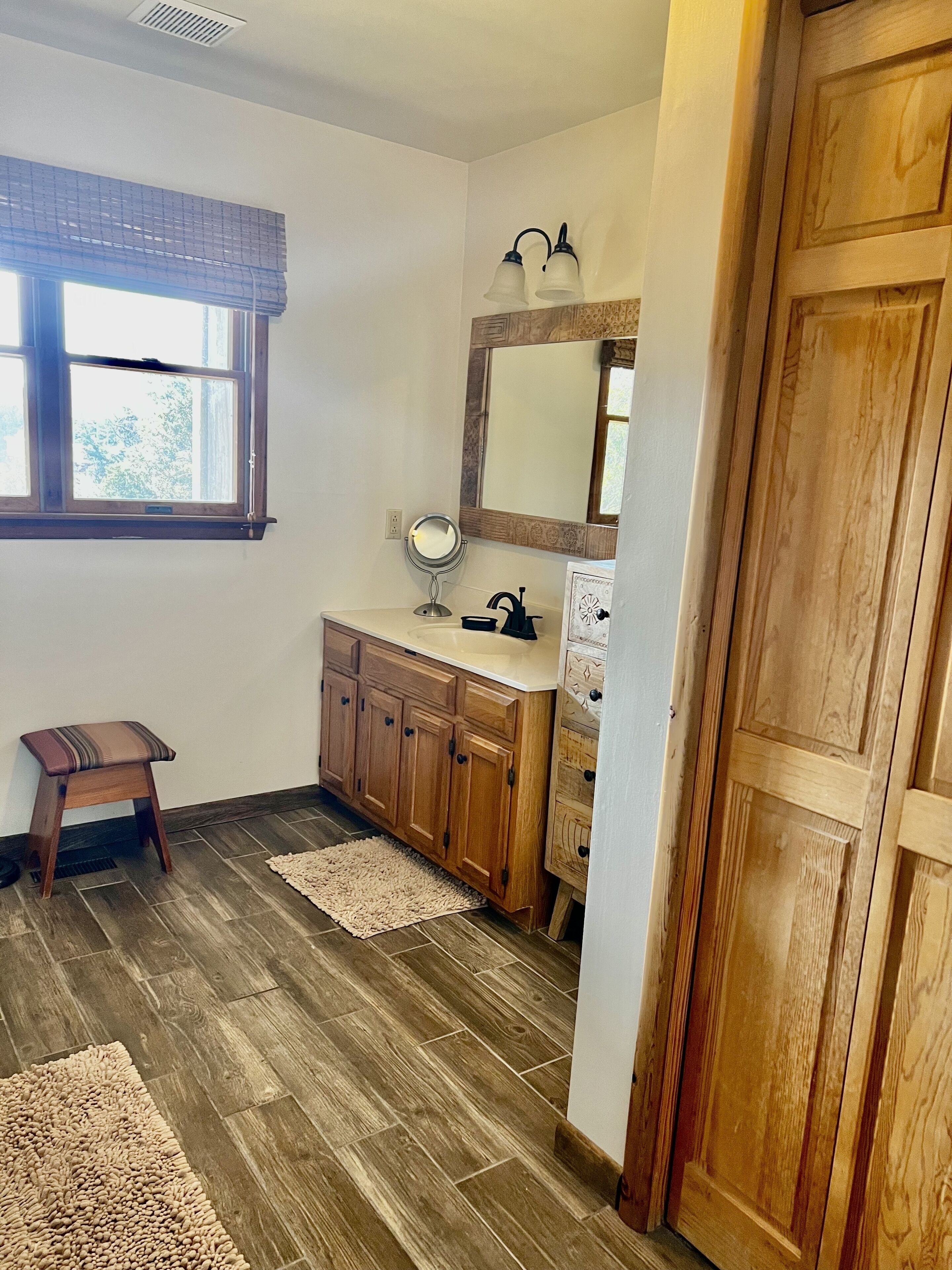 A bathroom with wooden cabinets, a sink, a mirror, and a window.