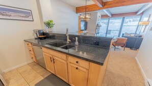 A kitchen with wooden cabinets, a granite countertop, and a double sink.
