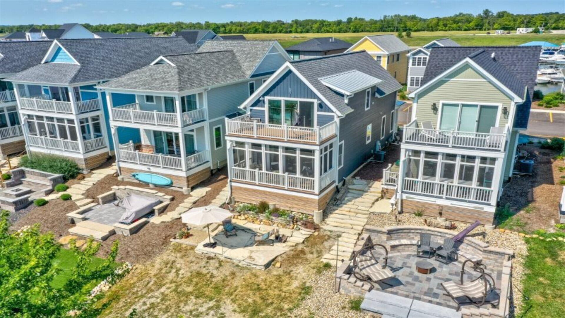 Une rangée de maisons de style côtier, dotées de balcons, d’une piscine et d’un patio aménagé avec du mobilier d’extérieur.