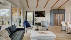 A modern living room with a sofa, chairs, a coffee table, and a kitchen area with a refrigerator. - Breathtaking Views of Lake Texoma's beaches/Islands and Highport Marina.
 (Pottsboro)