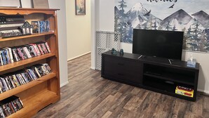 Un saló amb una biblioteca, un televisor de pantalla plana i un mural a la paret.