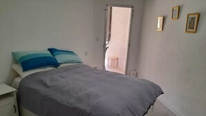 Un dormitorio con cama, mesitas de noche y una ventana.