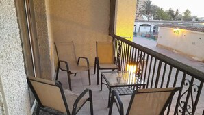 Un balcón con cuatro sillas y una mesa, barandilla y vista a la calle.