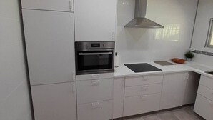 Una cocina moderna con armarios blancos, horno empotrado, campana extractora y ventana que proporciona luz natural.