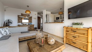 A modern living room with a sofa, coffee table, and a TV mounted on the wall. - HOUSE OF THE SEA (Callao Salvaje)