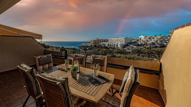 A terrace with a wooden table and chairs, potted plants, and a view of a coastal town and ocean. - HOUSE OF THE SEA (Callao Salvaje)
