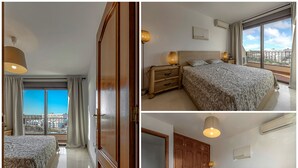 A hotel room with a large bed, a wardrobe, a nightstand, and a view of the city through large windows. - HOUSE OF THE SEA (Callao Salvaje)
