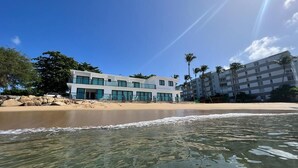 A beachfront hotel with a modern design, featuring a pool area and a view of the ocean.