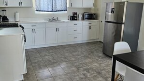 Eine moderne Küche mit weißen Schränken, einem Edelstahlkühlschrank, einer Mikrowelle und einer Kaffeemaschine.