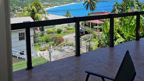 Ein Balkon mit Blick auf einen Strand und eine hügelige Landschaft.
