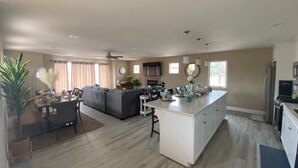 A spacious living area with a dining table, sofa, and kitchen with a large island. - Modern Rooftop Zen with Ocean and Mountain Views (Grover Beach)
