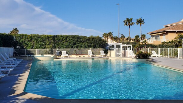 A swimming pool with lounge chairs, a lifeguard tower, and a fence.