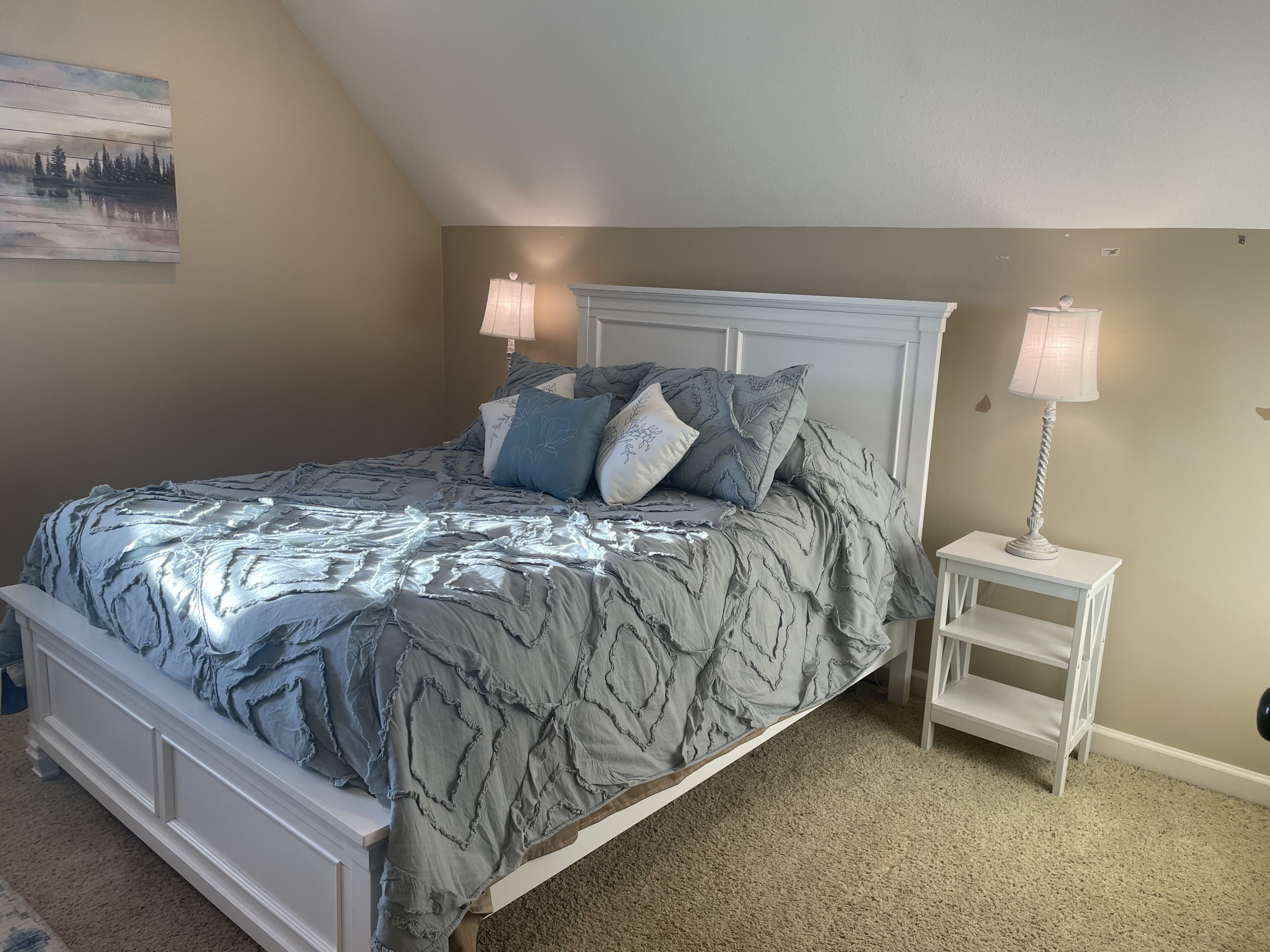 Una camera da letto con un letto, due comodini e un quadro appeso al muro.