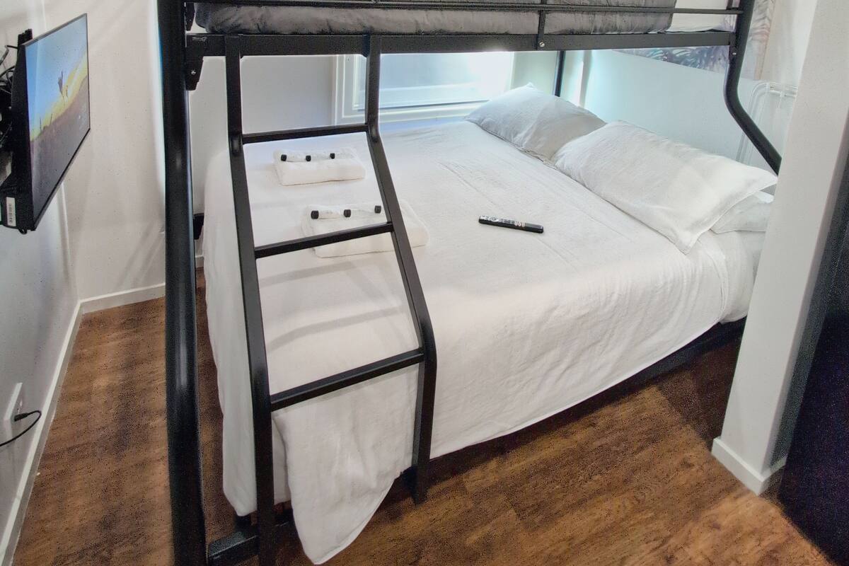 A bunk bed room with a window, an air conditioner, and a painting on the wall.