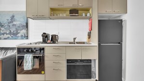 Una cucina compatta con forno a incasso, lavastoviglie e frigorifero.