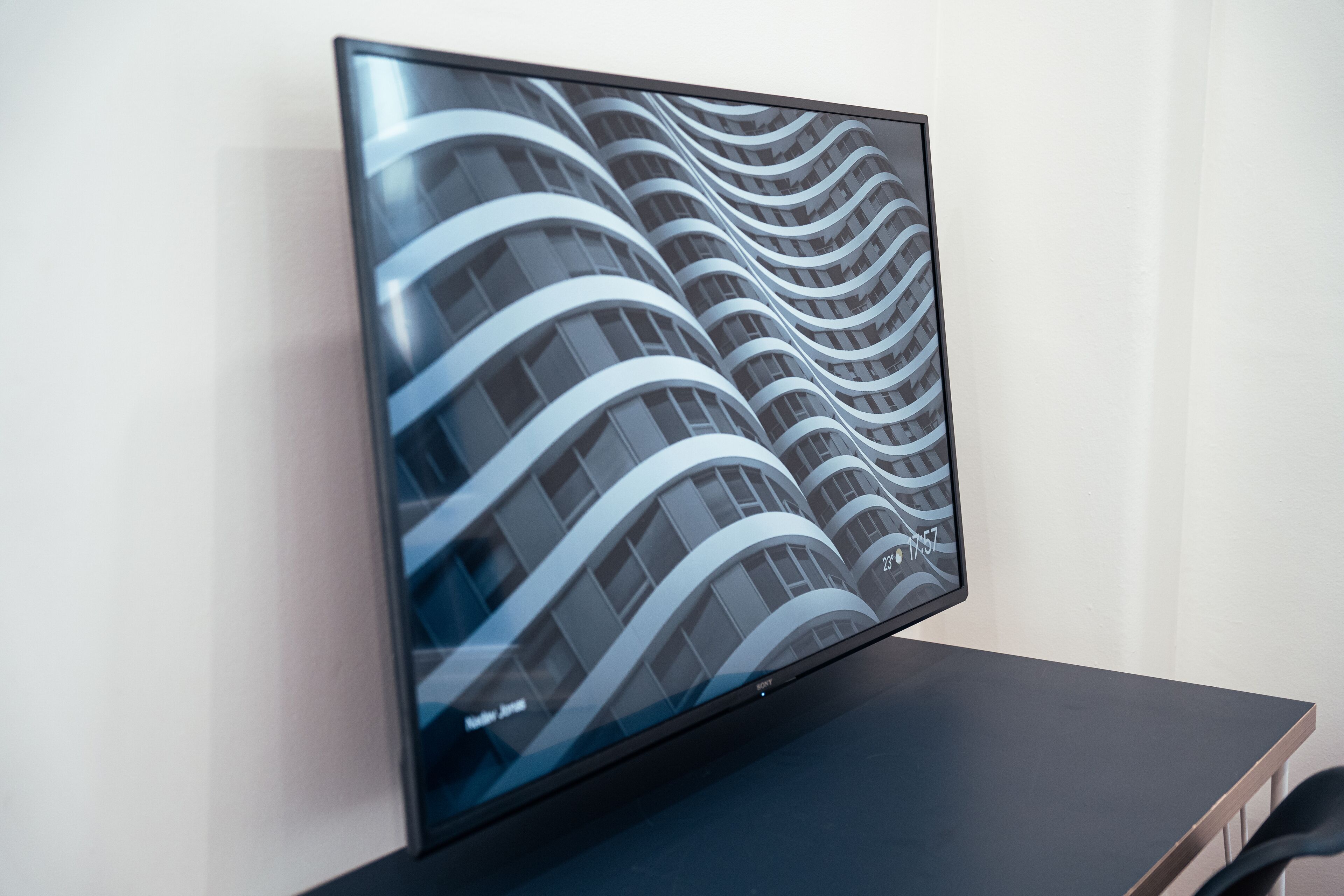 A flat-screen TV on a table displaying a modern building facade.