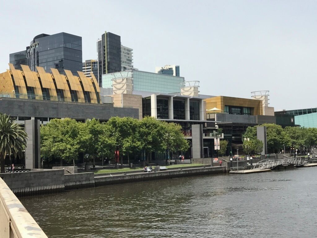 Vista al río con edificios modernos, un puente y un paseo arbolado.