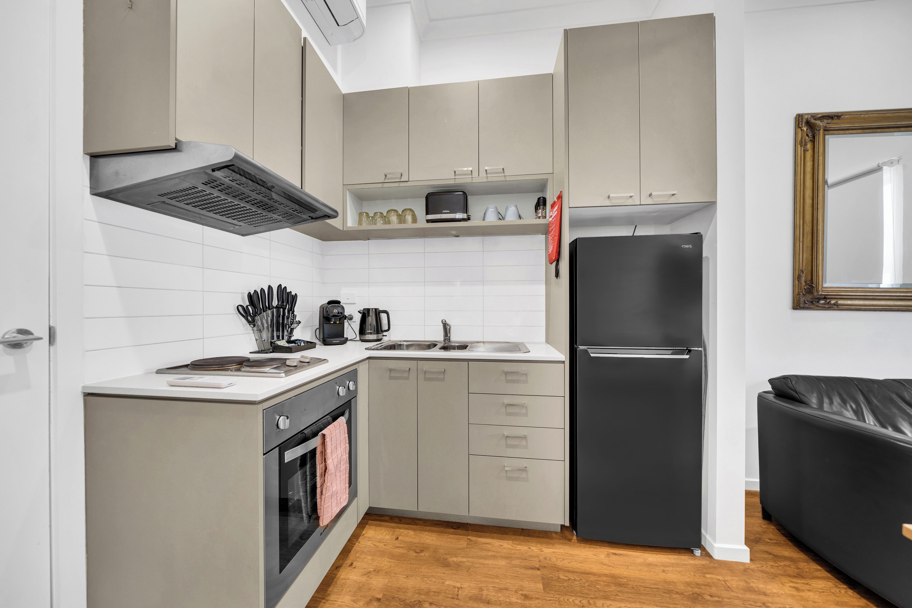 Una cocina compacta con horno integrado, un refrigerador y un microondas.