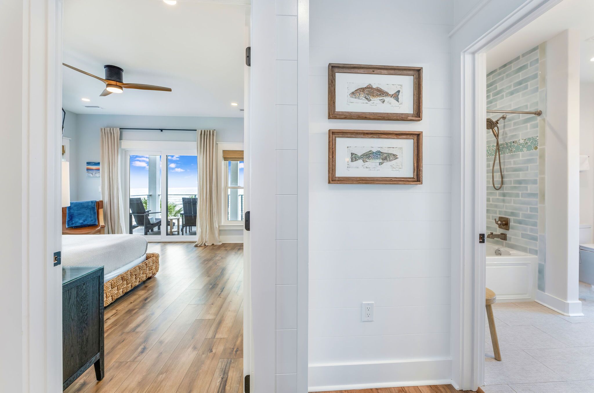 A modern bathroom with a shower, a bathtub, and two framed fish illustrations on the wall.