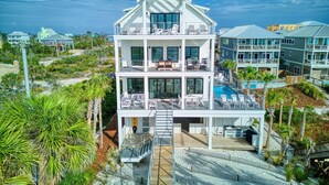 Une propriété en bord de mer, composée de plusieurs étages, dot ée d’une piscine, de balcons et d’un jardin bien entretenu.