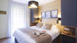 Un dormitorio moderno con una cama grande, cabecera de madera y una mesita de noche con lámpara.