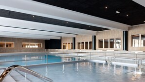 Una piscina interior moderna con agua cristalina, barandillas de metal y un diseño contemporáneo.