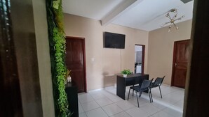 A dining area with a table and chairs, a TV mounted on the wall, and a ceiling fan. - Pousada Meireles Praia (Fortaleza)