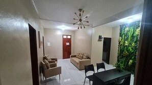 A living room with a sofa, two armchairs, a dining table with chairs, a ceiling light fixture, and a door with a sign. - Pousada Meireles Praia (Fortaleza)