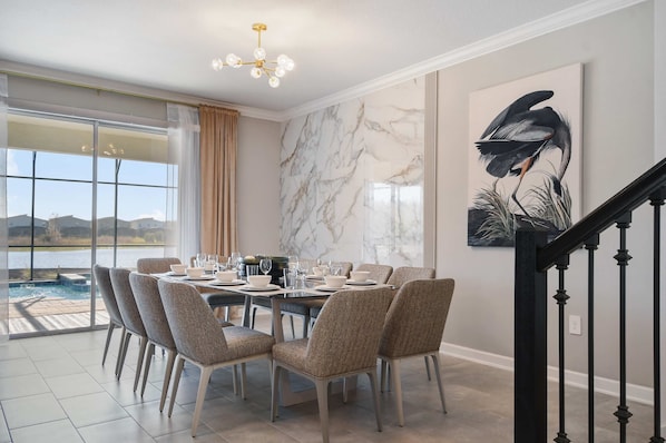 A dining area with a table set for six, surrounded by chairs, a large window with a view, and a marble wall.