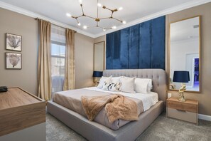 Quarto com uma cama grande, mesa de cabeceira, espelho e obras de arte na parede.