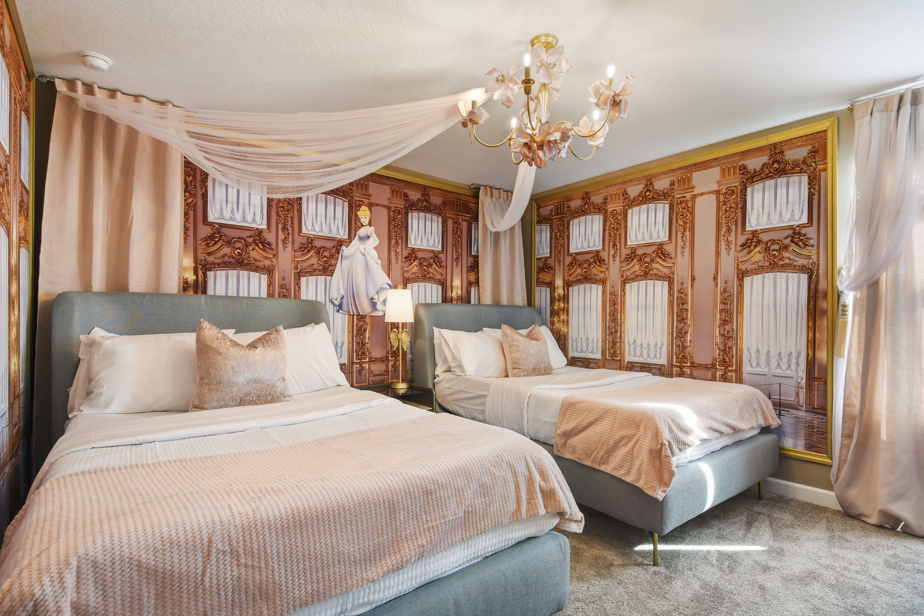 A luxurious bedroom with two beds, ornate wall paneling, and a chandelier.