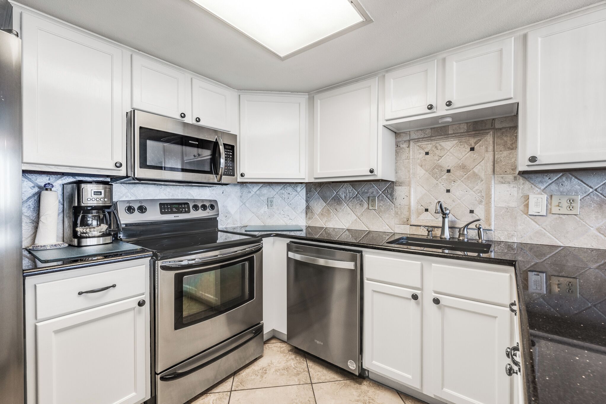 A modern kitchen with white cabinetry, stainless steel appliances, a microwave, oven, and dishwasher.