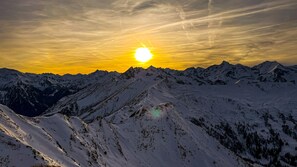 A mountain landscape with snow-covered peaks and a setting sun.