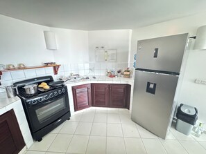 A kitchen with a stove, oven, refrigerator, and white tiled walls.