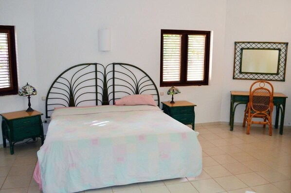 A bedroom with a bed, two nightstands, a chair, a desk, and a mirror.