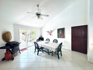 A dining area with a ceiling fan, a table with chairs, a grill, and a door.